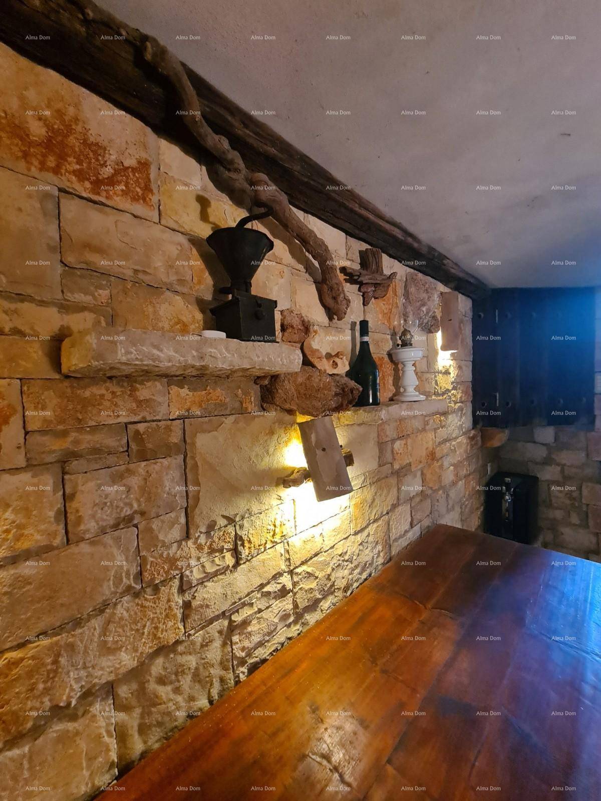 Rustikaler Kellerraum mit Steinwänden, Holztisch und traditioneller Dekoration an der Wand.