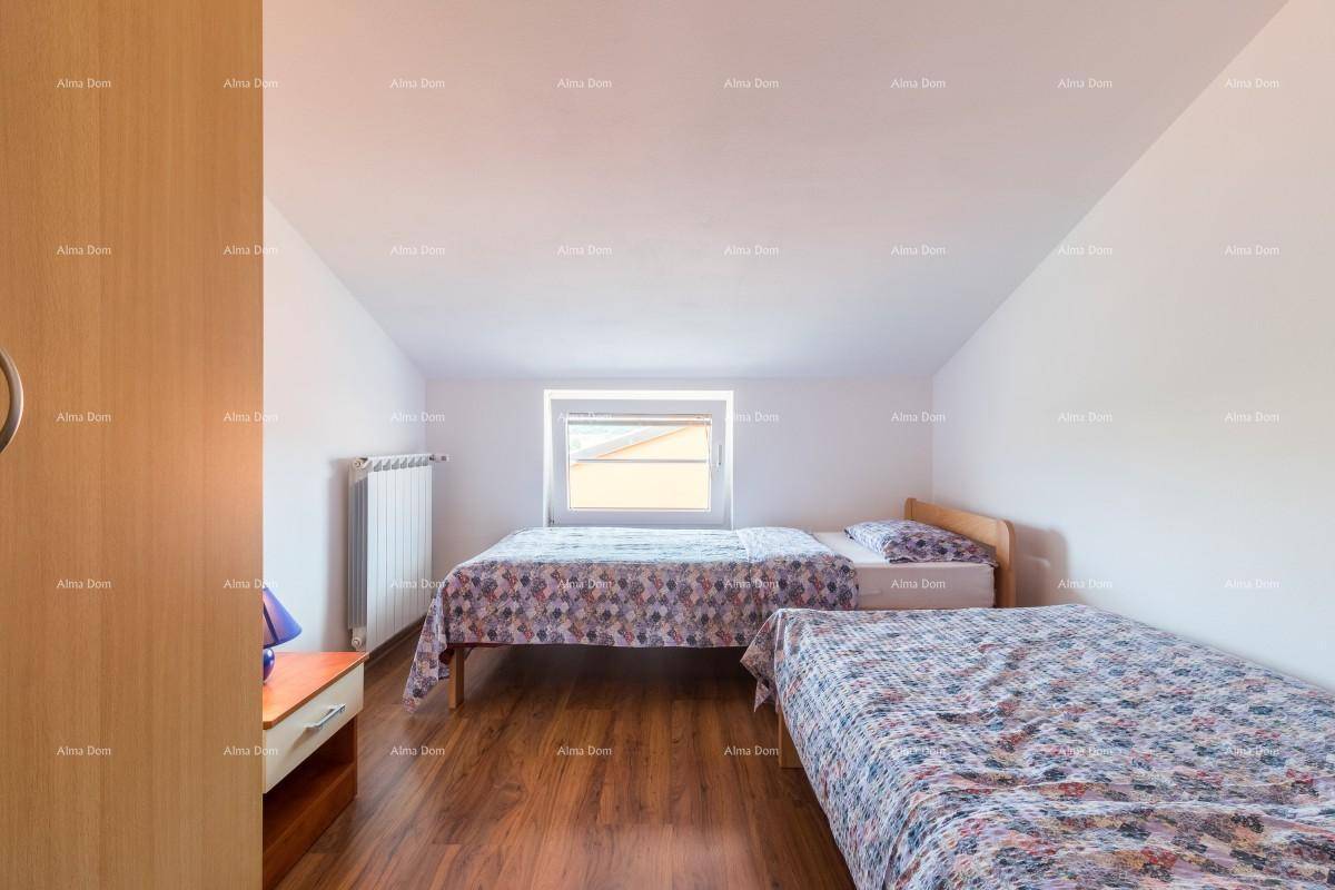 Helles Schlafzimmer im Dachgeschoss mit zwei Einzelbetten, Holzboden und Dachfenster.