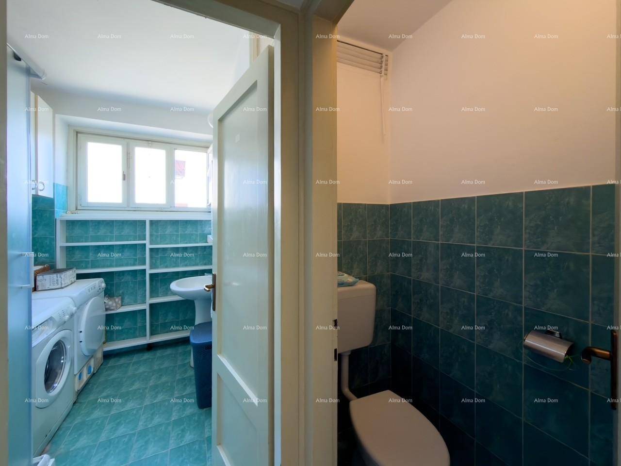 Badezimmer mit grünen Fliesen, Toilette und Waschmaschine.