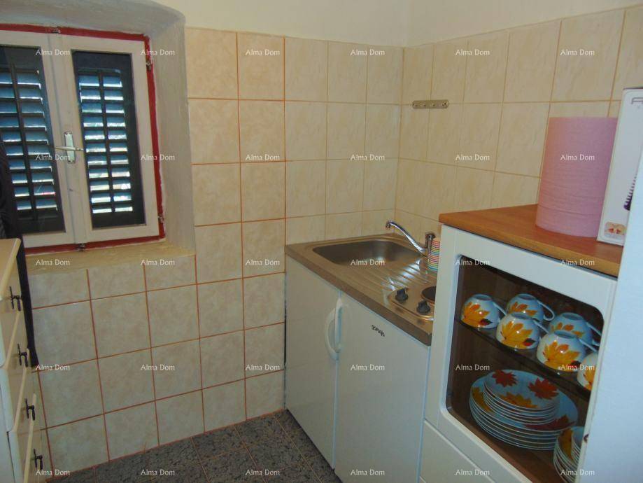 Kleine Küche mit Fliesenwänden, Spüle und einem Fenster mit Fensterläden.