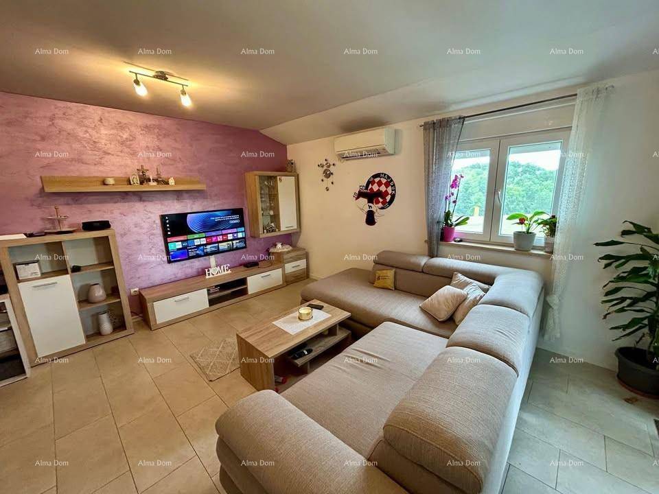 Wohnbereich mit großem Sofa, Fernseher und Fenster, das viel Tageslicht hereinlässt.