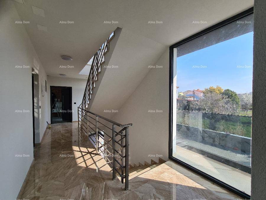 Heller Treppenaufgang mit modernem Geländer und großem Fenster für viel Tageslicht.