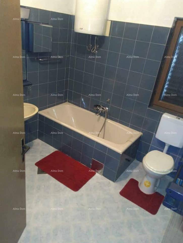 Badezimmer mit blauen Fliesen, Badewanne, Toilette und Waschbecken unter einem Fenster.