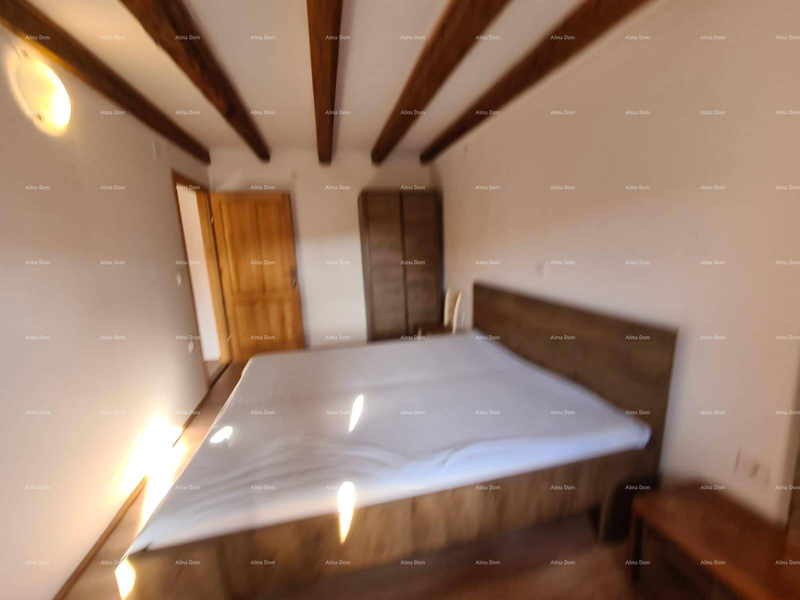 Geräumiges Schlafzimmer mit großem Bett, Holzbalkendecke und hellem Holzboden, lichtdurchflutet durch das Fenster.