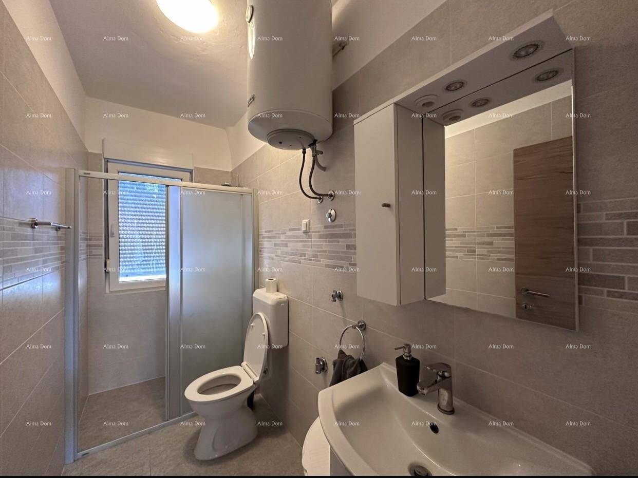 Gefliestes Badezimmer mit Waschbecken, Toilette, Duschkabine und Fenster für Tageslicht.