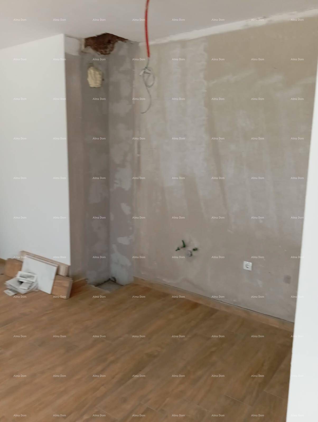 Unfertiger Innenraum mit Holzoptik-Fliesenboden und unverputzten Wänden, bereit für den Ausbau.
