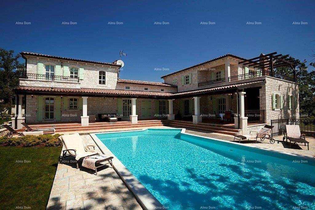 Weitläufiger Garten mit großem Pool und der beeindruckenden Steinvilla unter strahlend blauem Himmel.
