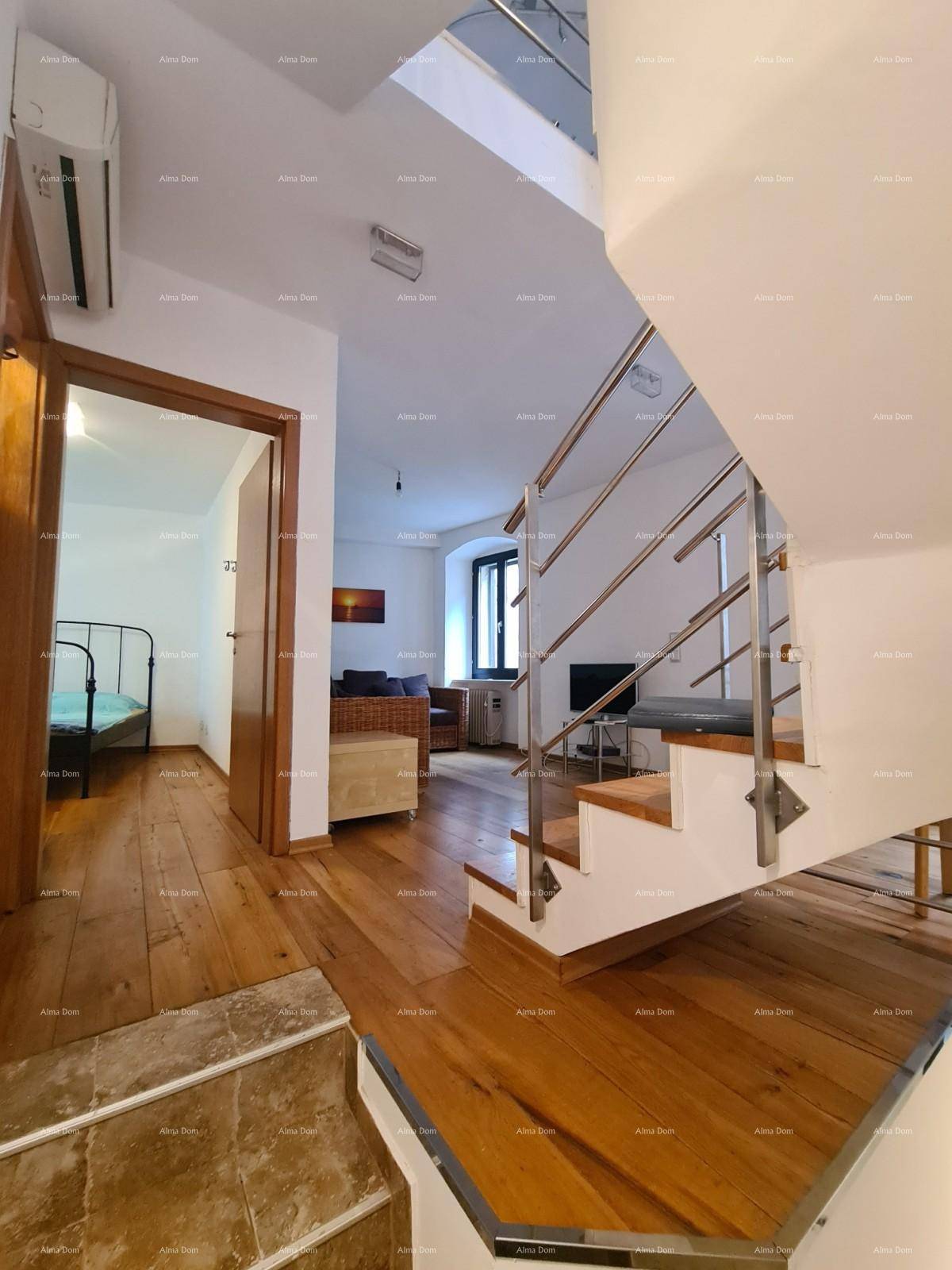 Offener Wohnbereich mit Holzboden, moderner Treppe und Zugang zu einem Schlafzimmer.