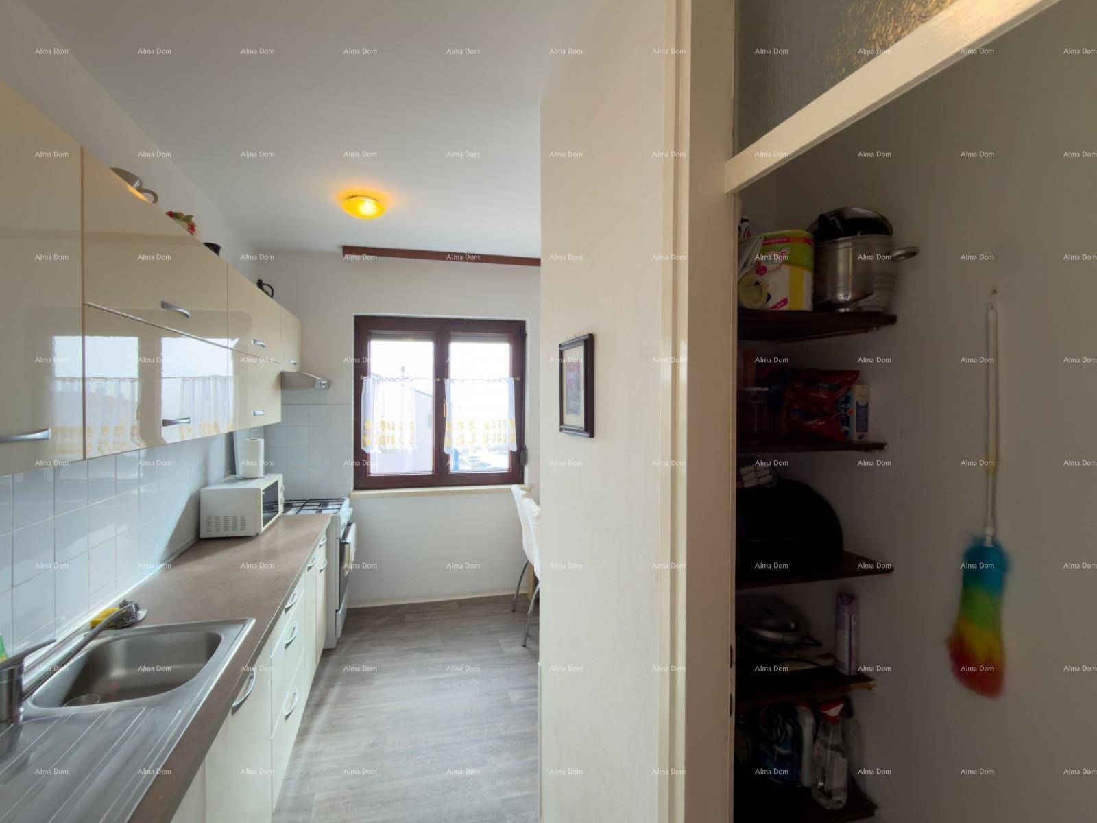 Küche mit beigen Schränken, Fliesenrückwand und integrierter Speisekammer.