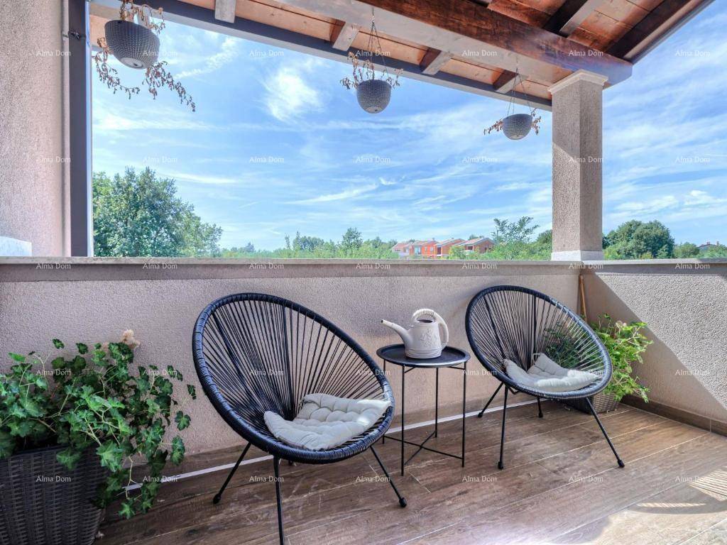 Möblierter Balkon mit bequemen Stühlen und einem weiten Blick ins Grüne.