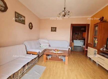 Gemütliches Wohnzimmer mit hellen Wänden, Ecksofa und Holzboden, offen zu einem weiteren Raum.