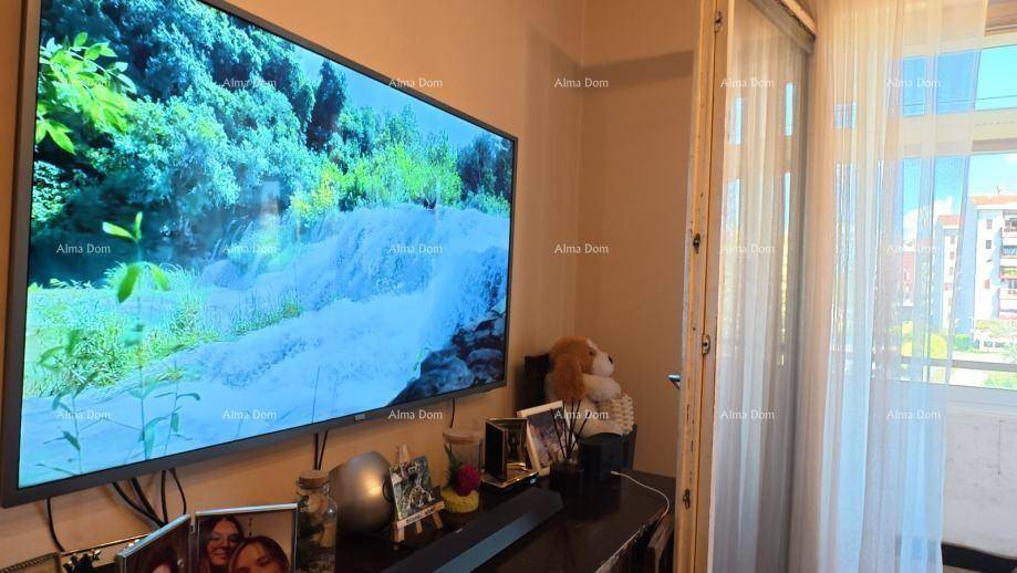 Wohnzimmer mit großem Flachbildfernseher und Zugang zum Balkon.