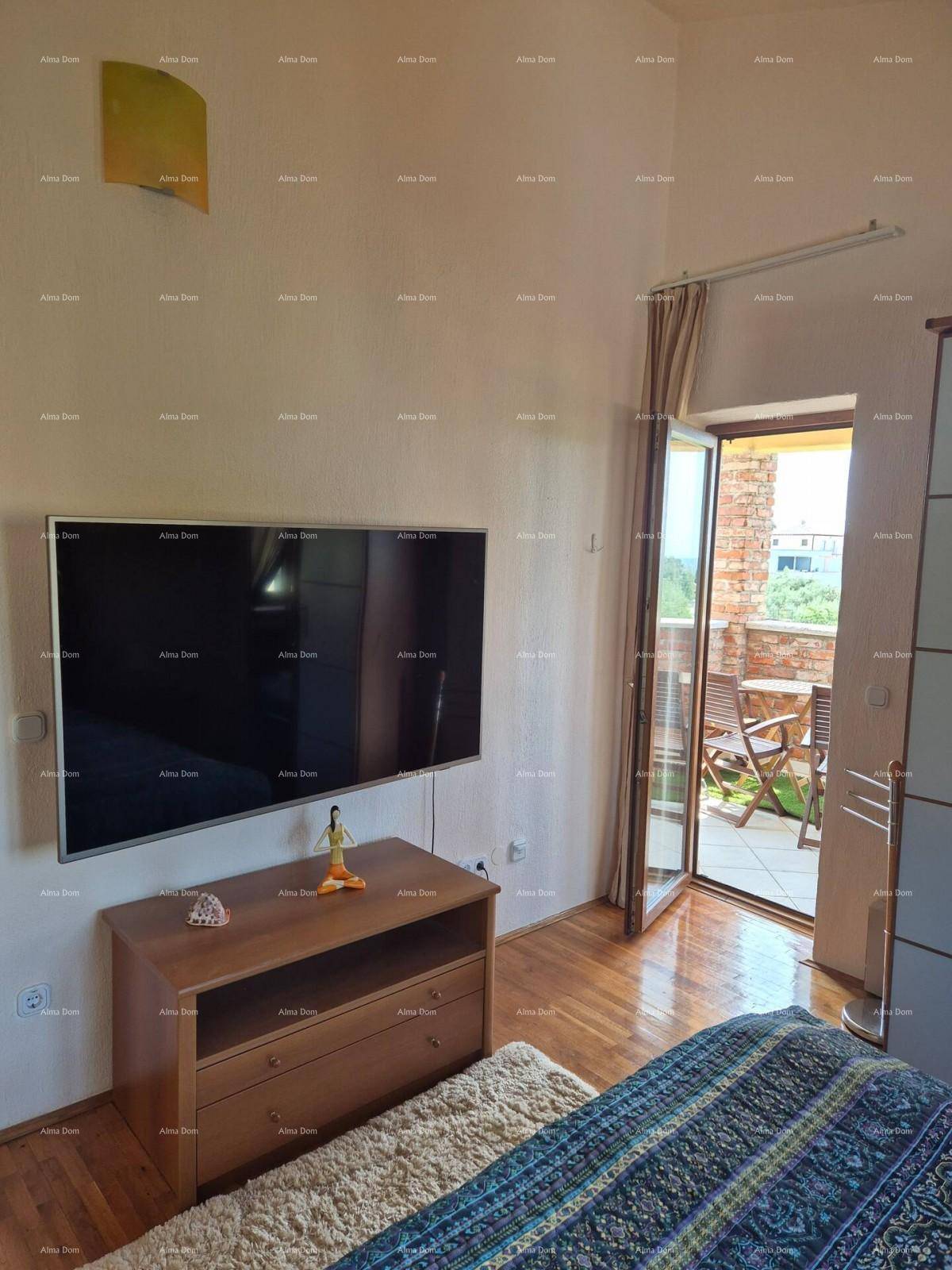 Schlafzimmer mit Holzboden, Wandfernseher und Zugang zu einem möblierten Außenbereich.