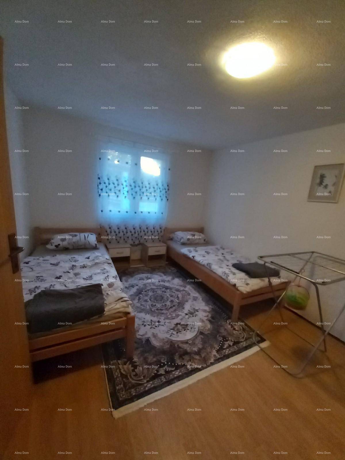 Helles Schlafzimmer mit zwei Einzelbetten, Holzfußboden und einem Wäscheständer.