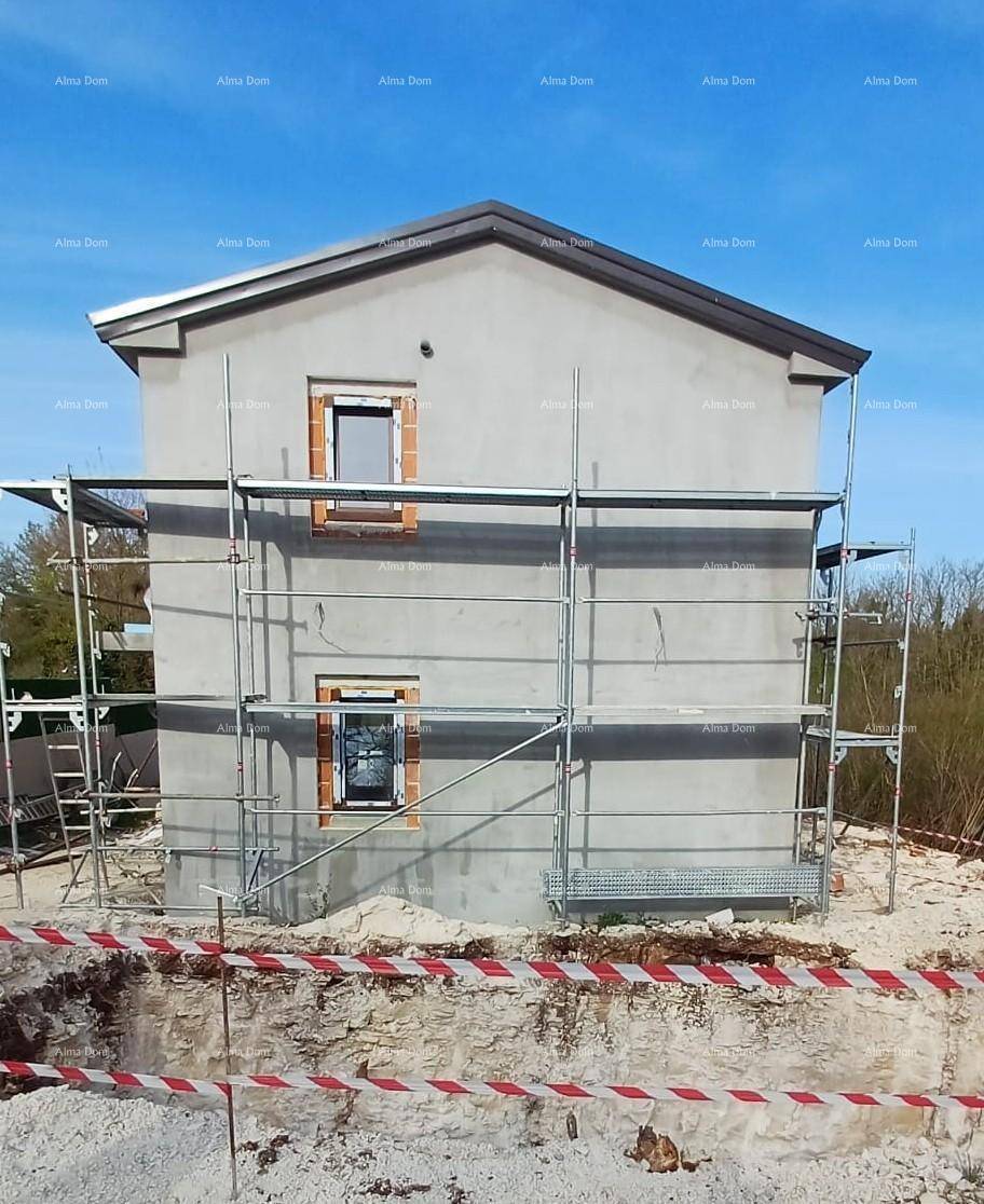 Rückansicht eines im Bau befindlichen Hauses mit Gerüst und vorbereiteten Fenstern.