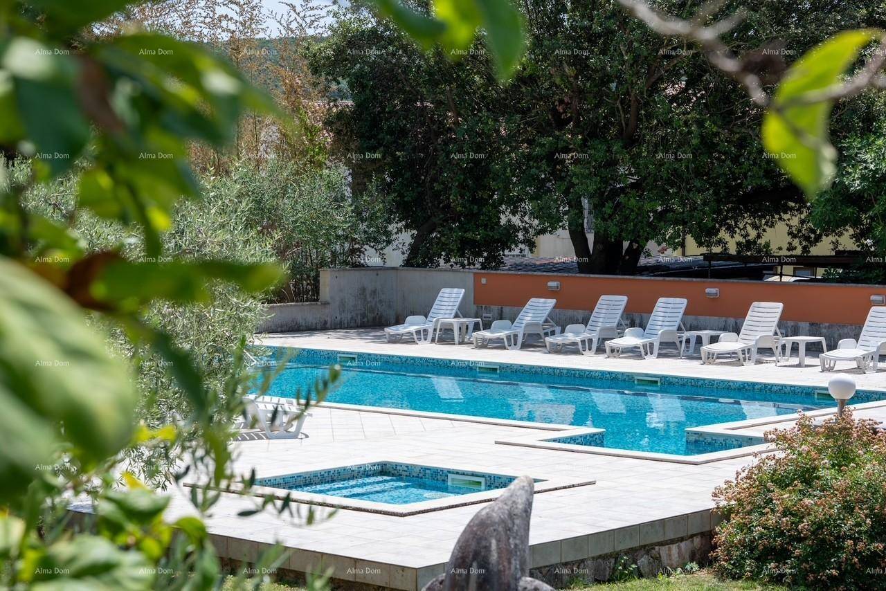 Detailansicht des Pools mit blauen Mosaikfliesen, umgeben von Liegestühlen und üppiger Vegetation.
