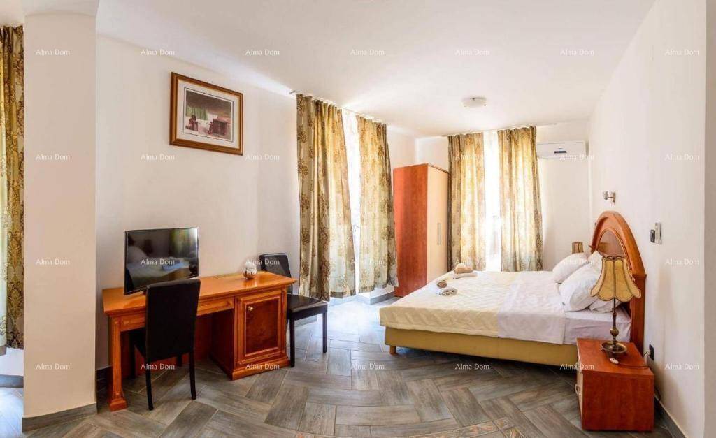 Geräumiges Schlafzimmer mit Doppelbett, Schreibtisch und großen Fenstern mit Vorhängen.