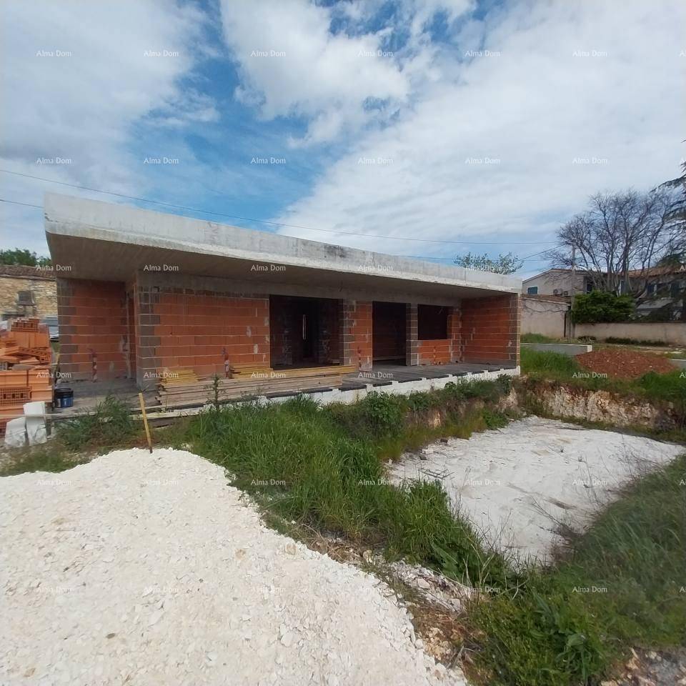 Rohbau einer modernen Villa mit Ziegelwänden und Betonplatte, umgeben von Baustelle und Natur.