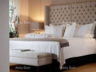 Elegantes Schlafzimmer mit großem Bett, gepolstertem Kopfteil und einer Sitzbank am Fußende.