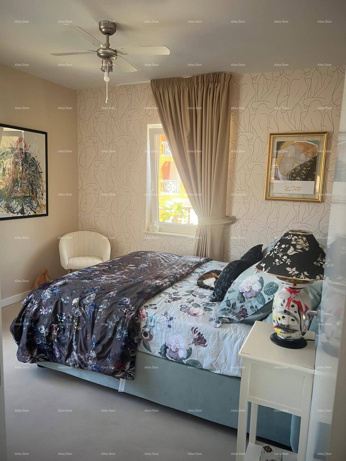 Schlafzimmer mit Doppelbett, gemusterter Tapete und Deckenventilator, bietet eine helle und freundliche Atmosphäre.