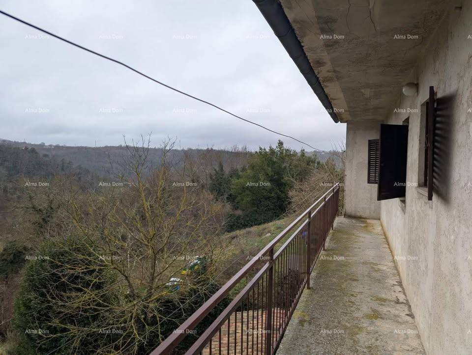 Langer Balkon mit Metallgeländer und weitem Blick über eine bewaldete Landschaft.