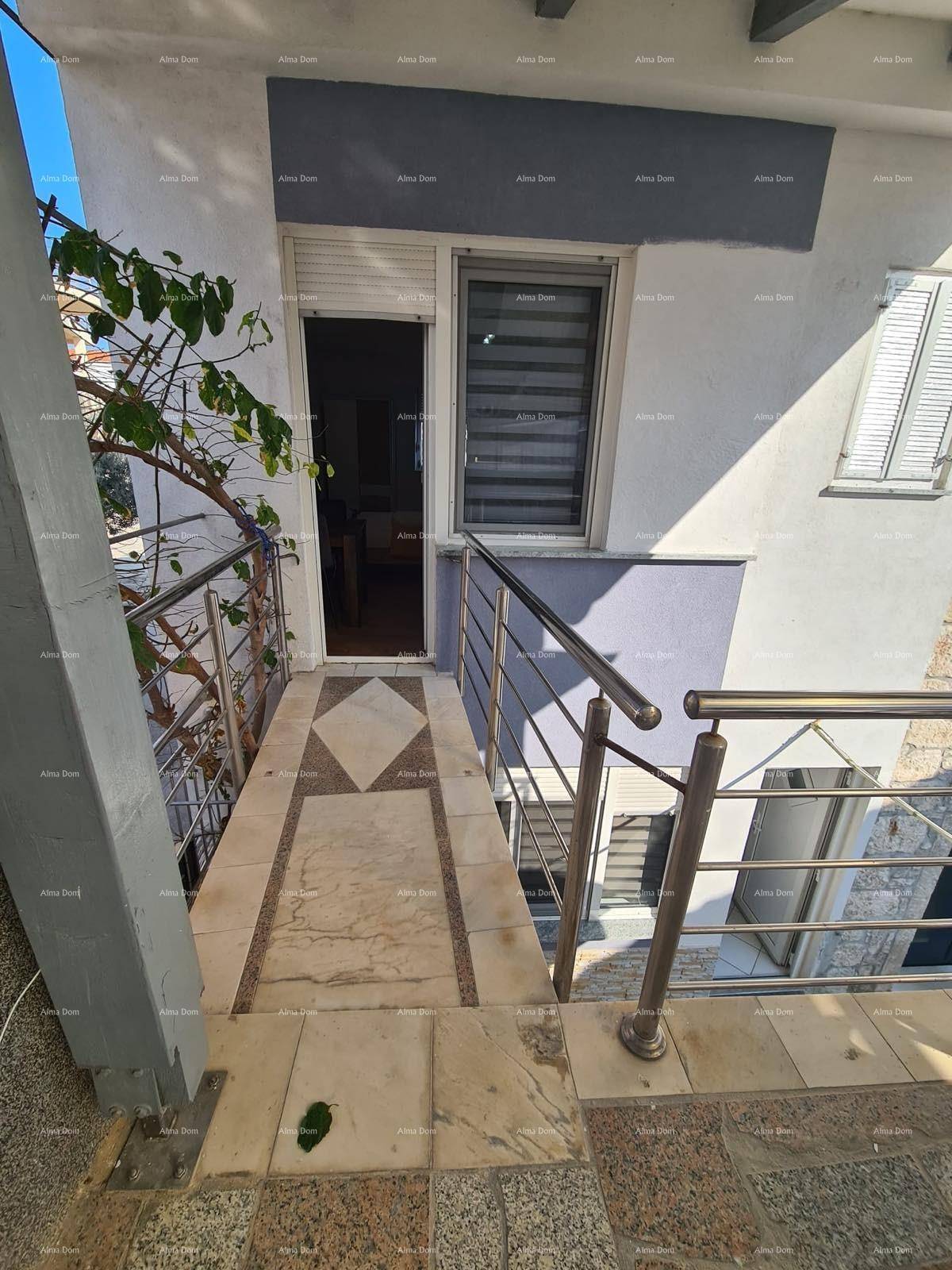 Balkon mit Fliesenboden und Metallgeländer, führt zu einem Eingang.
