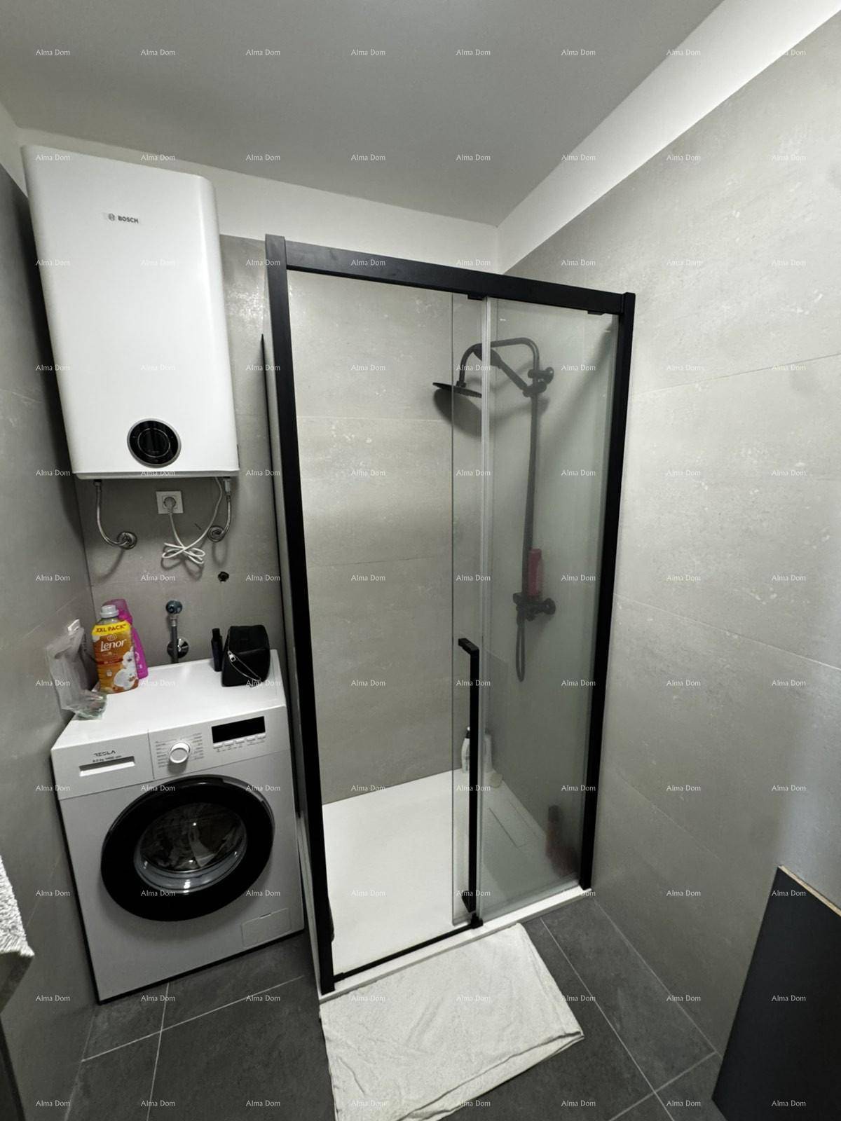 Badezimmer mit Duschkabine, Waschmaschine und Warmwasserbereiter, praktisch eingerichtet.