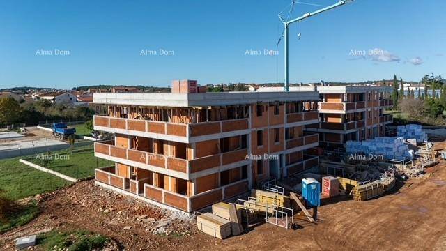 Baustelle mit mehreren Gebäuden im Rohbau, Baumaterialien und einem großen Kran.