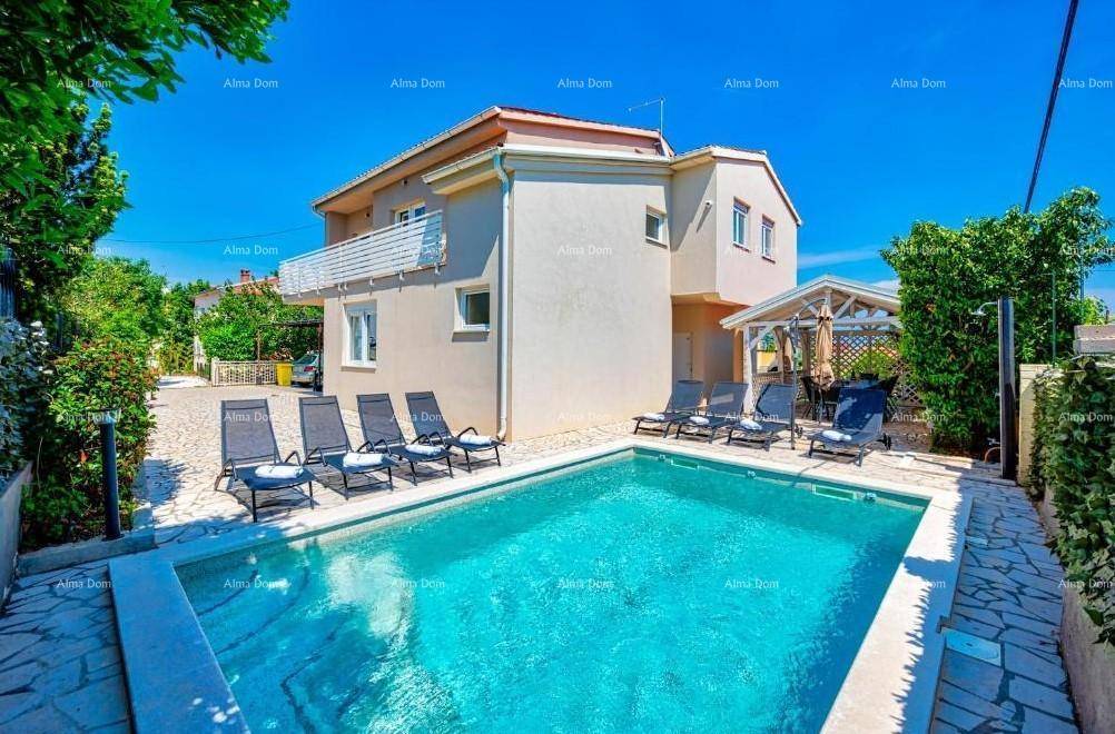 Sonniger Poolbereich mit Liegestühlen und der modernen Fassade des Wohnhauses.