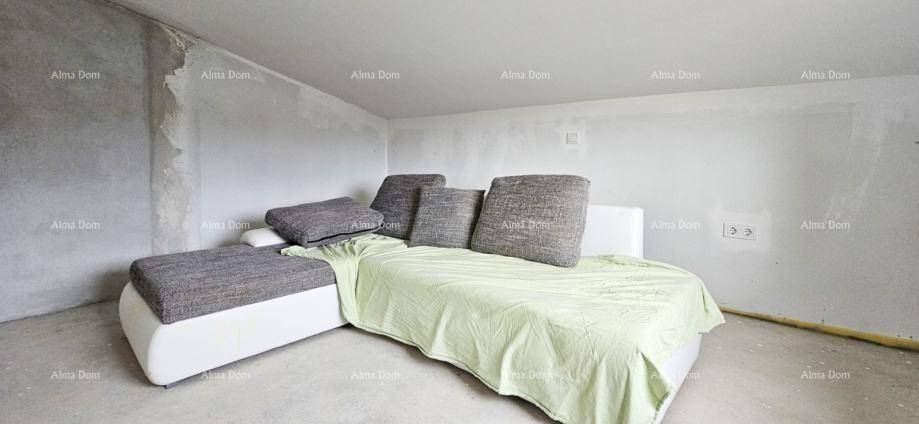 Blick auf das unfertige Wohnzimmer mit Sofa, Betonboden und Dachschräge, bereit für die Fertigstellung.