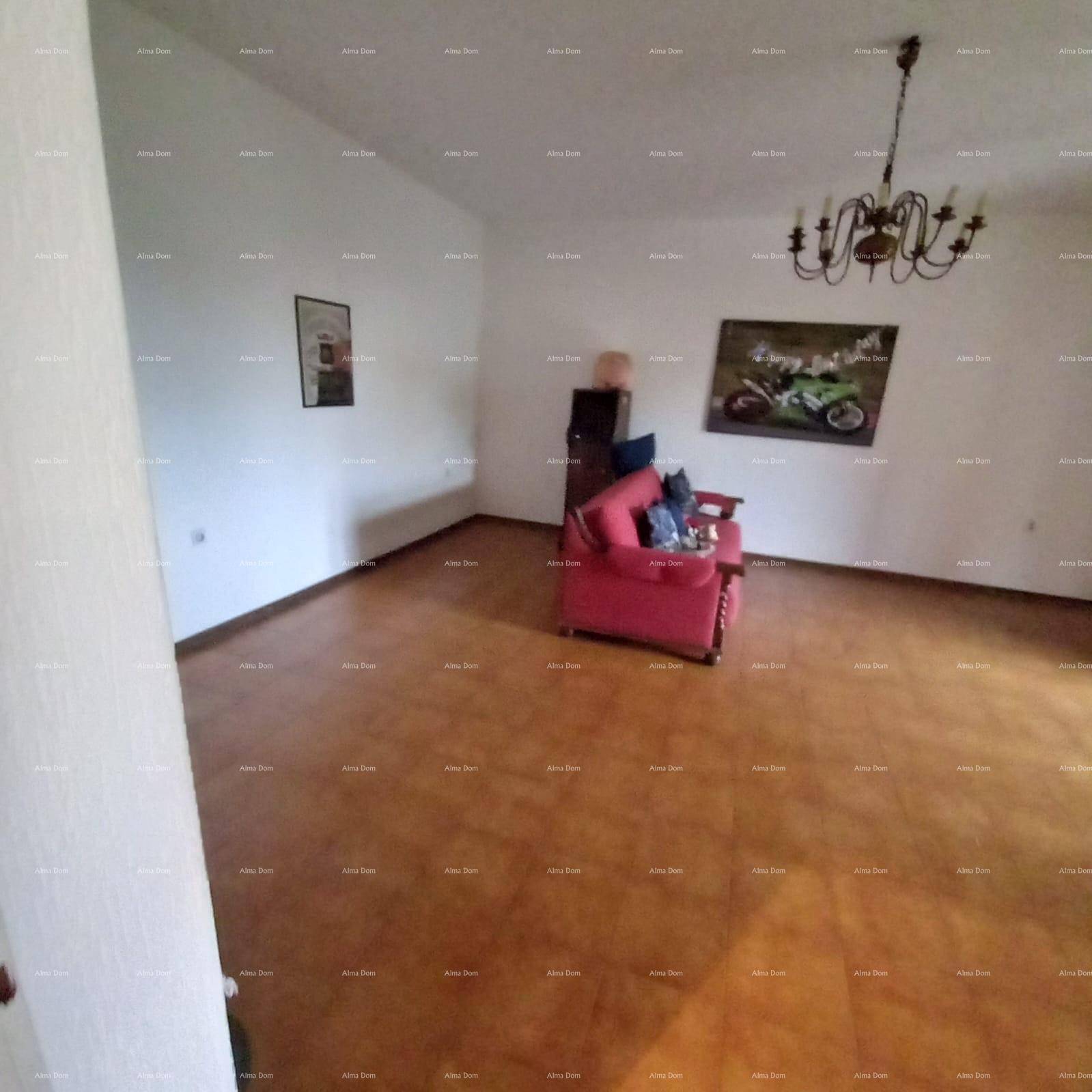 Geräumiges Wohnzimmer mit braunen Fliesen und einem einzelnen roten Sessel.