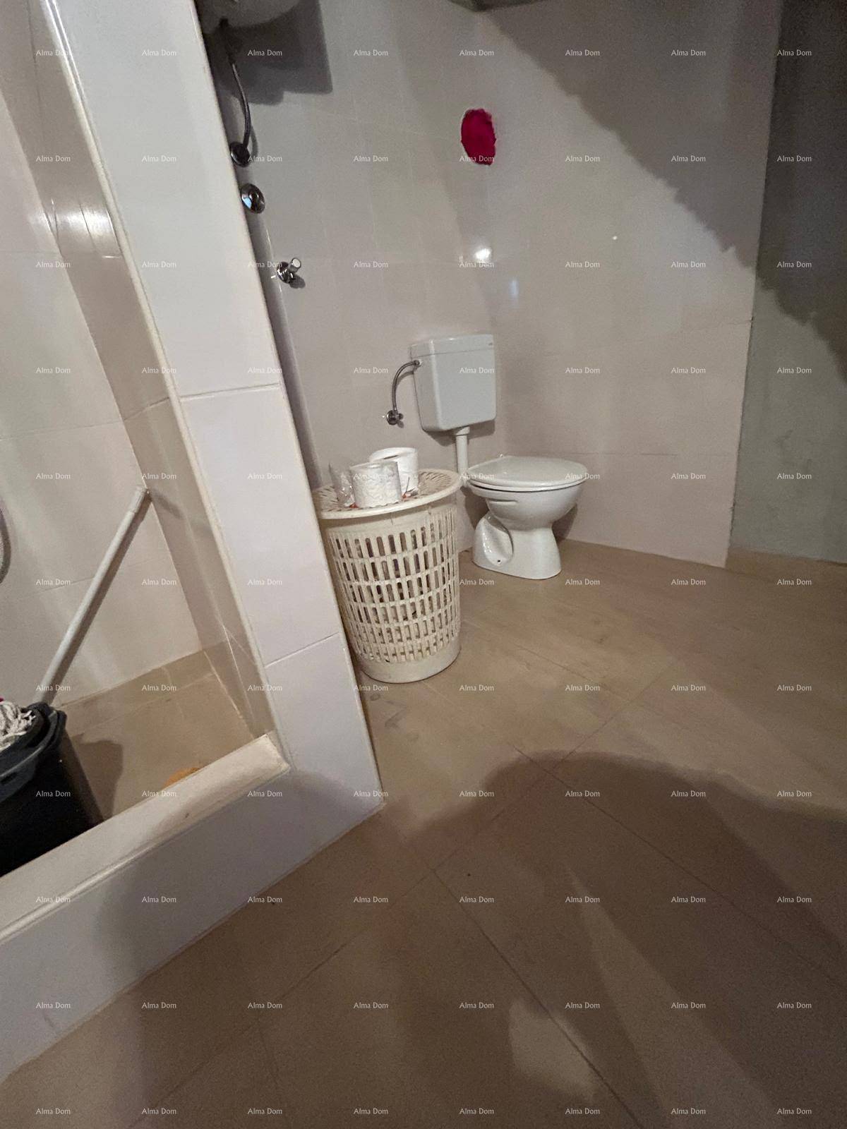 Helles Badezimmer mit Duschbereich und Toilette, im Rohbauzustand mit Fliesenboden.