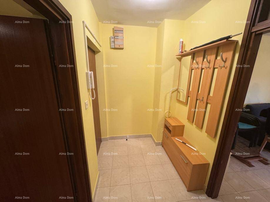 Heller Eingangsbereich mit gelben Wänden, Fliesenboden und einer einfachen Garderobe.