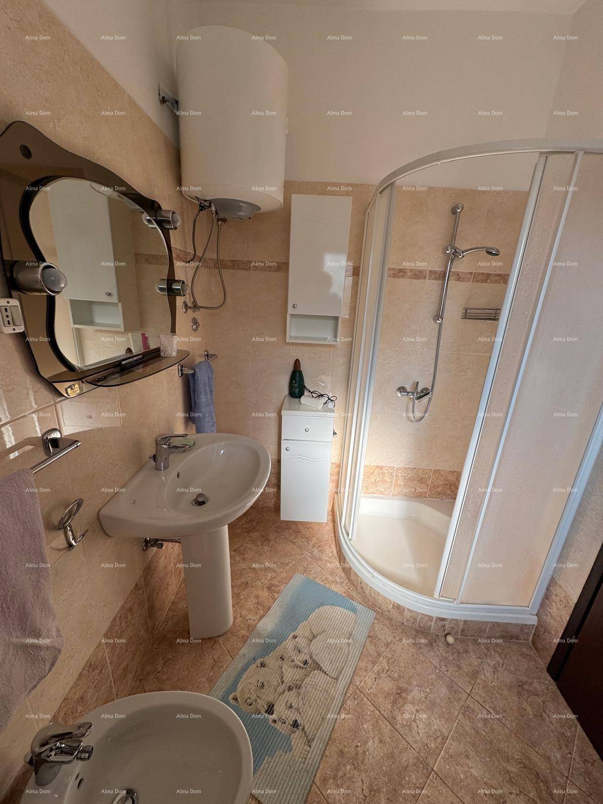 Badezimmer mit Duschkabine, Waschbecken und Boiler, ausgestattet mit beigen Fliesen.