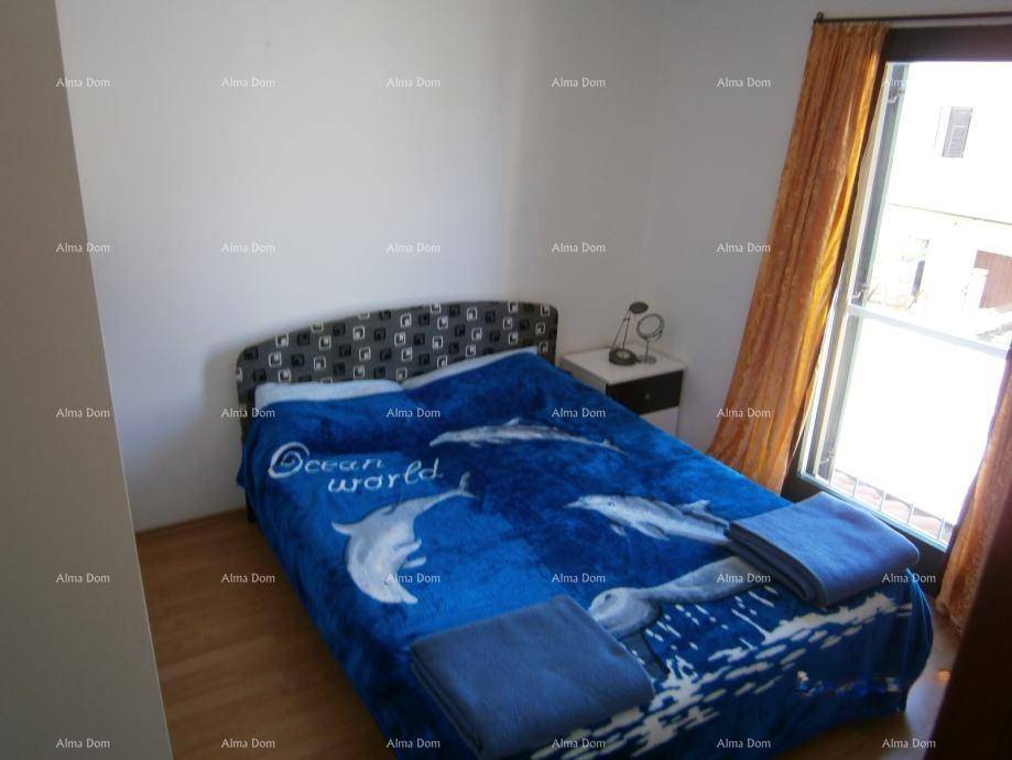 Schlafzimmer mit Doppelbett, Holzboden und Fenster mit Vorhängen.