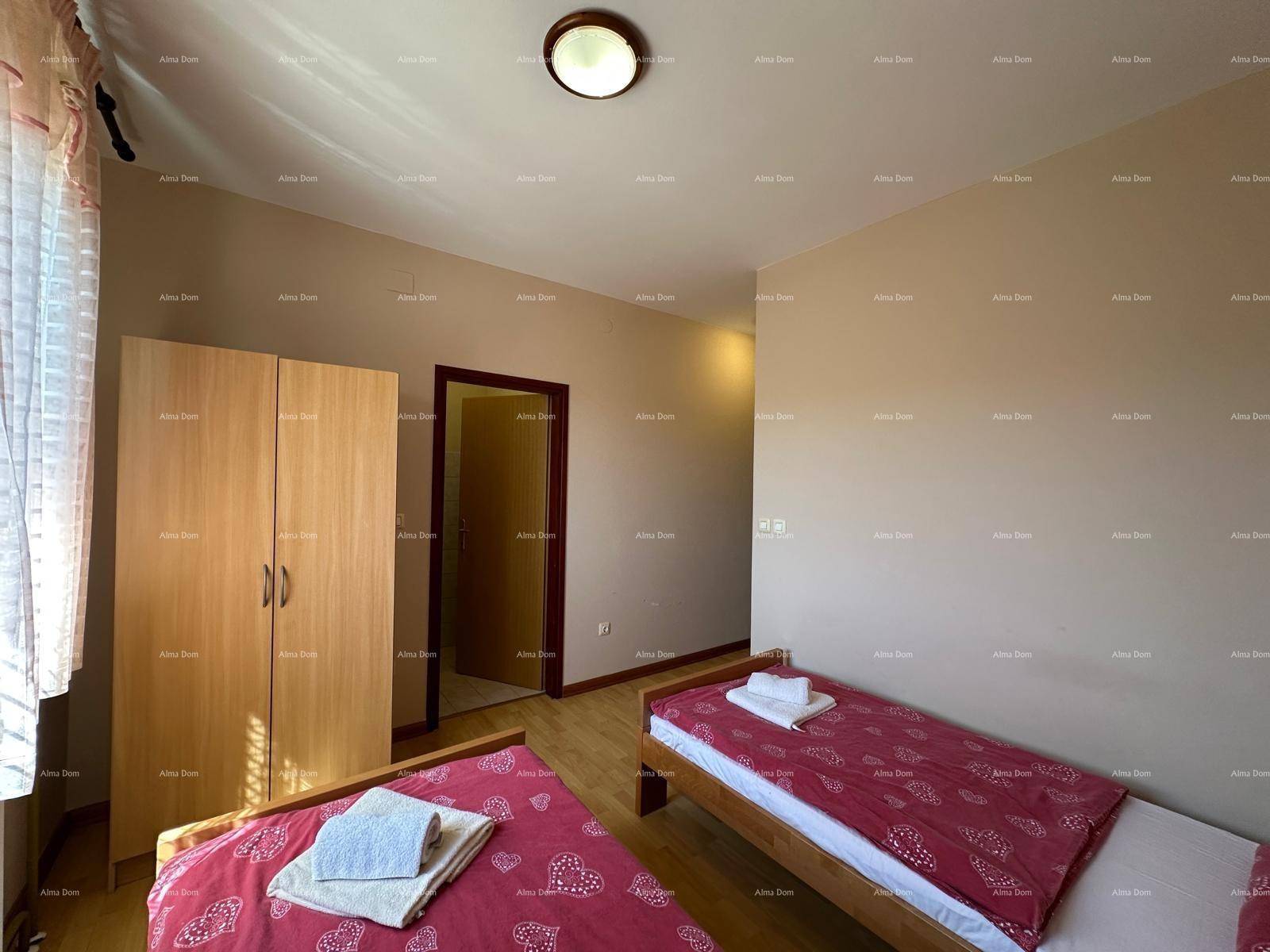 Helles Schlafzimmer mit zwei Einzelbetten und Holzboden, funktional und einfach eingerichtet.