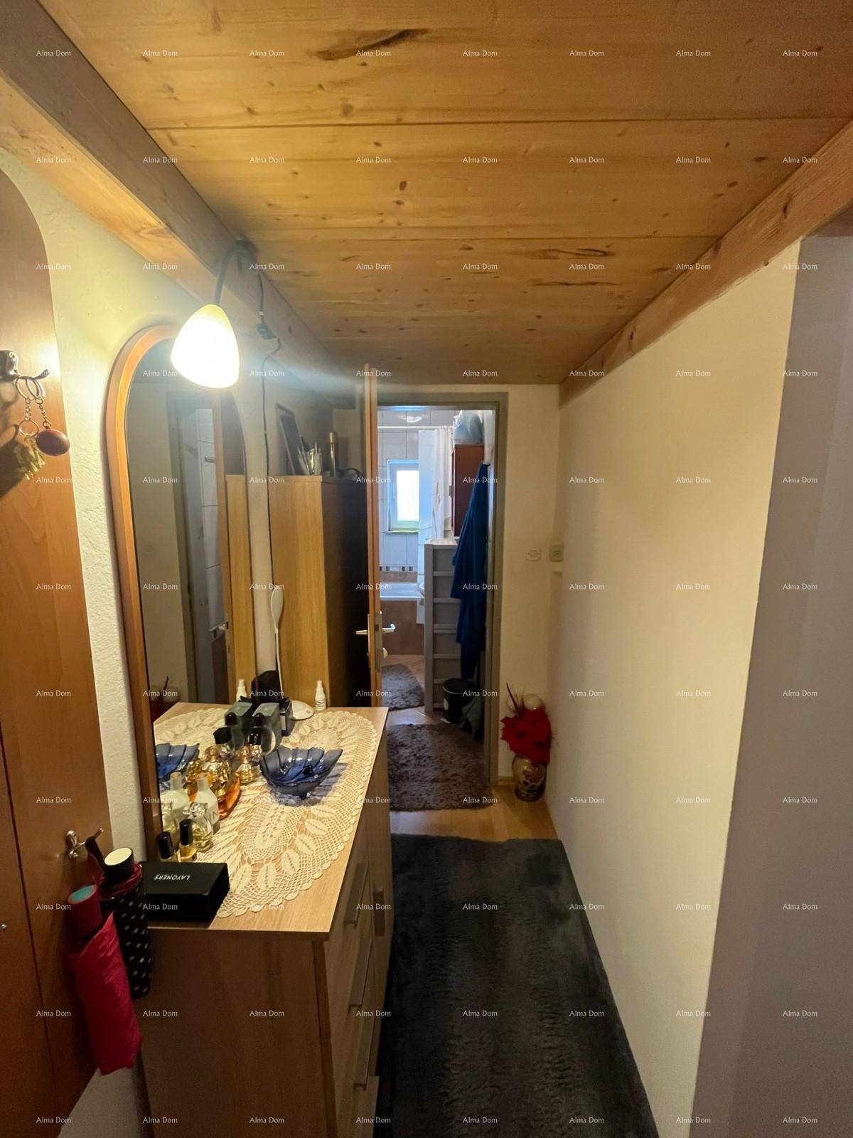 Flur mit Holzbalkendecke, Kommode und Blick in ein angrenzendes Badezimmer.