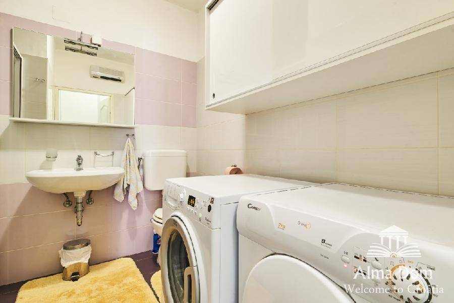 Praktischer Hauswirtschaftsraum mit Waschmaschine, Trockner und Waschbecken.