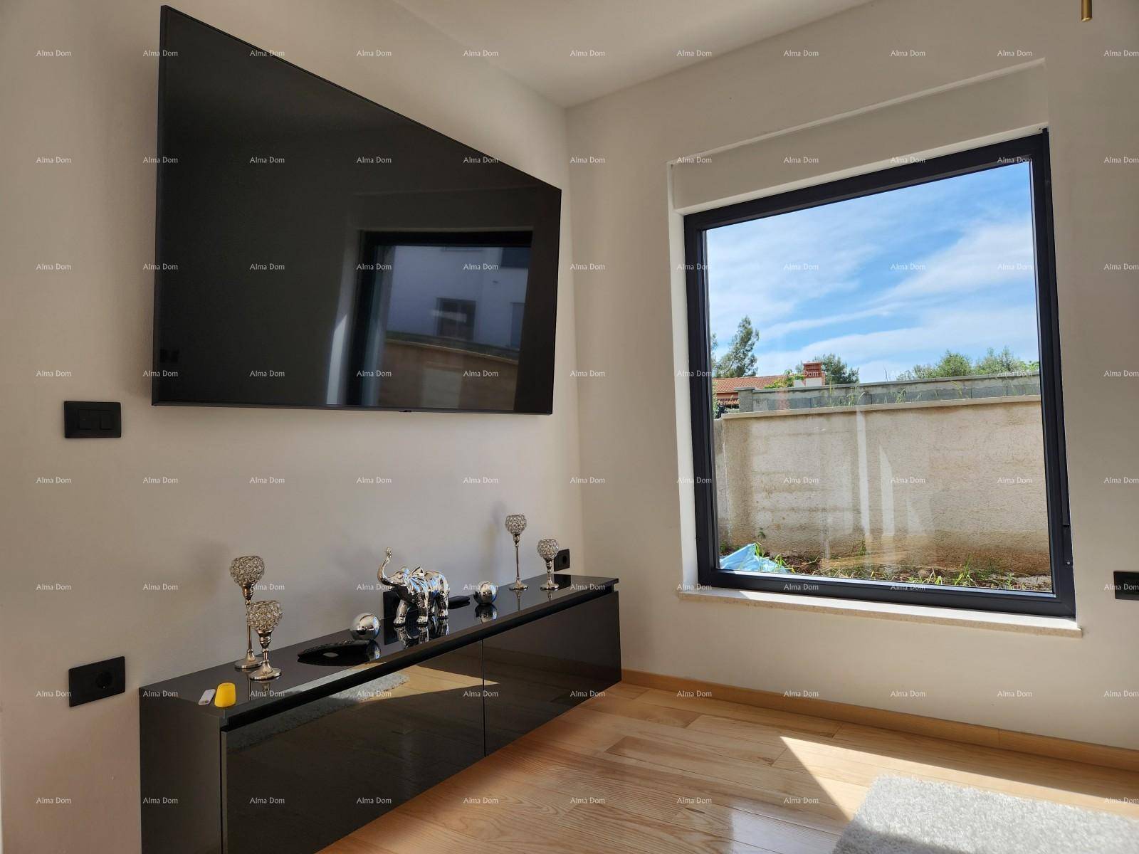 Detailansicht des Wohnzimmers mit großem Fenster und modernem Wandfernseher.