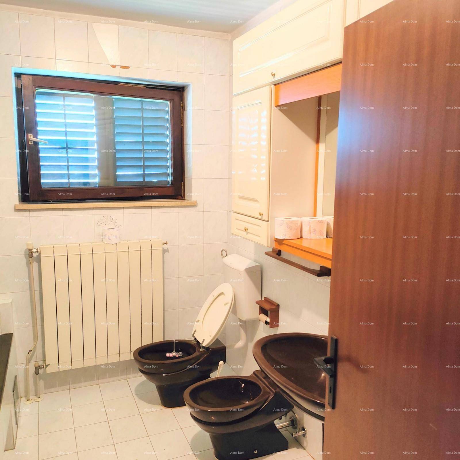Badezimmer mit weißen Fliesen, Fenster, Toilette, Bidet und einem Heizkörper an der Wand.