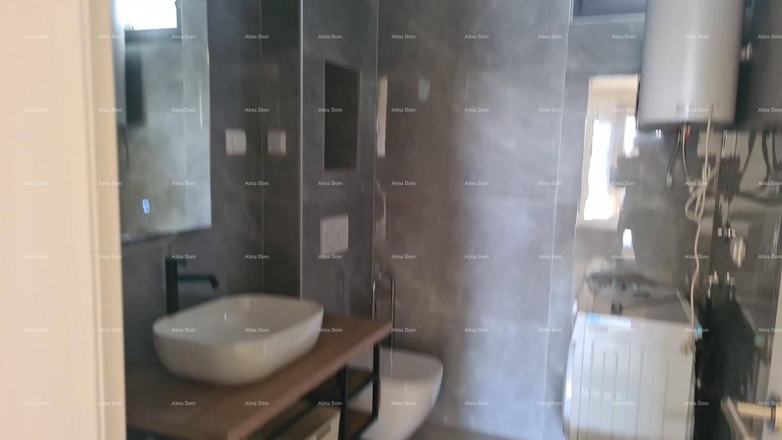 Modernes Badezimmer mit grauen Fliesen, Waschbecken, Toilette und Waschmaschine.