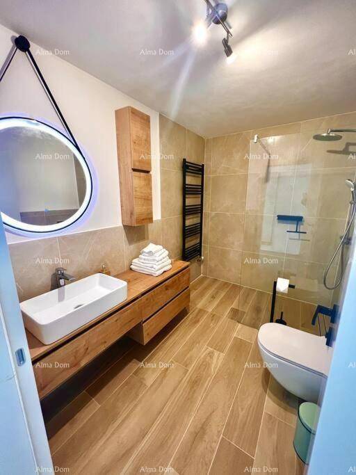 Elegantes Badezimmer mit Holzoptikfliesen, modernem Waschtisch und beheiztem Handtuchhalter.