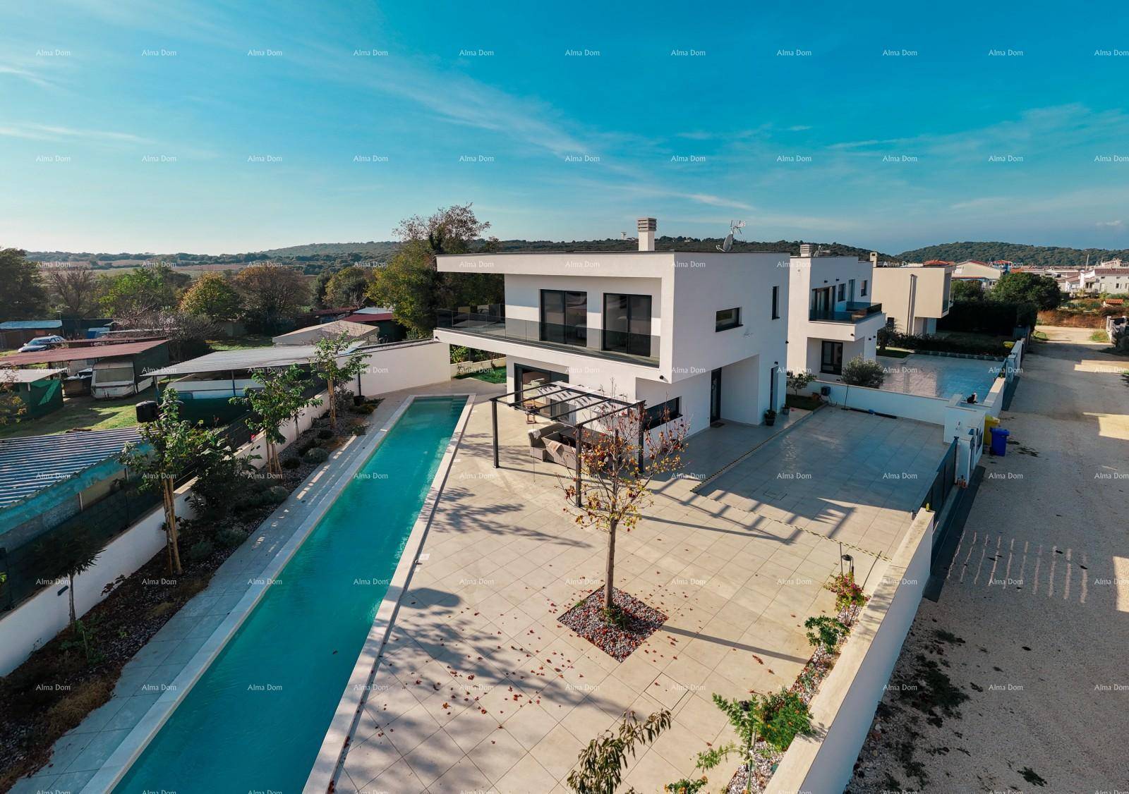 Luftaufnahme der modernen Villa mit langem Pool und großzügiger Außenanlage unter blauem Himmel.
