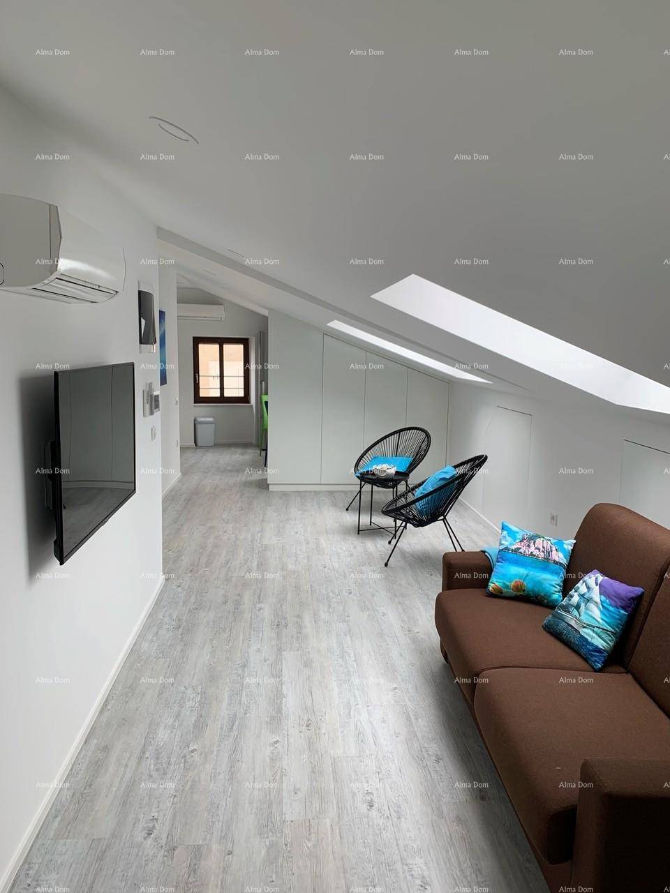 Geräumiger Wohnbereich mit Sofa, Fernseher und Blick auf die Sitzecke unter dem Dachfenster.