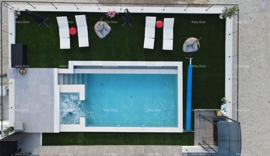 Draufsicht auf den modernen Poolbereich mit Whirlpool, Sonnenliegen und Kunstrasenfläche.