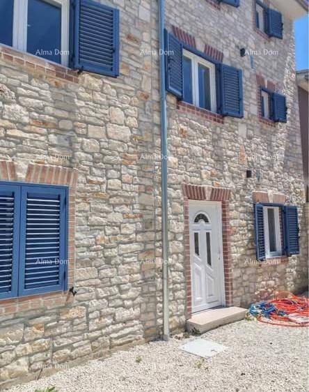 Traditionelle Steinfassade des Gebäudes mit blauen Fensterläden und weißer Eingangstür.