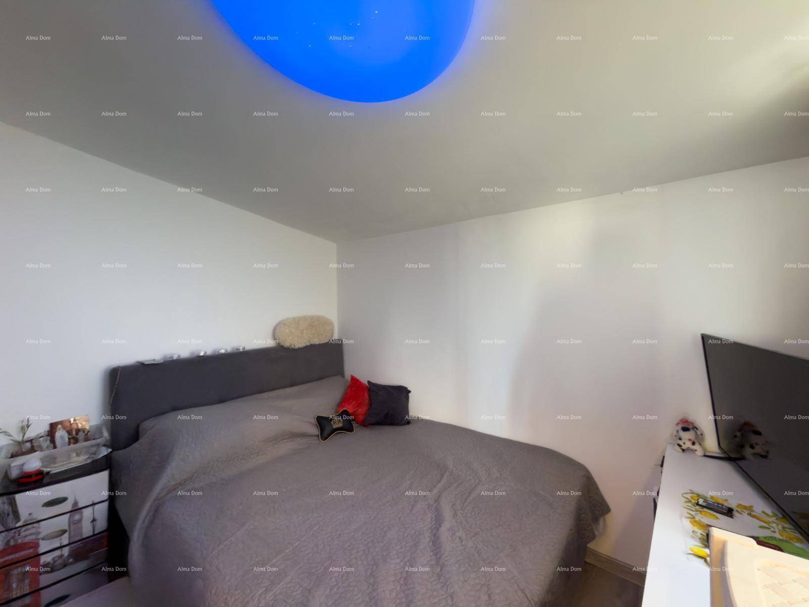 Modernes Schlafzimmer mit Doppelbett, Fernseher und dekorativer Deckenbeleuchtung.