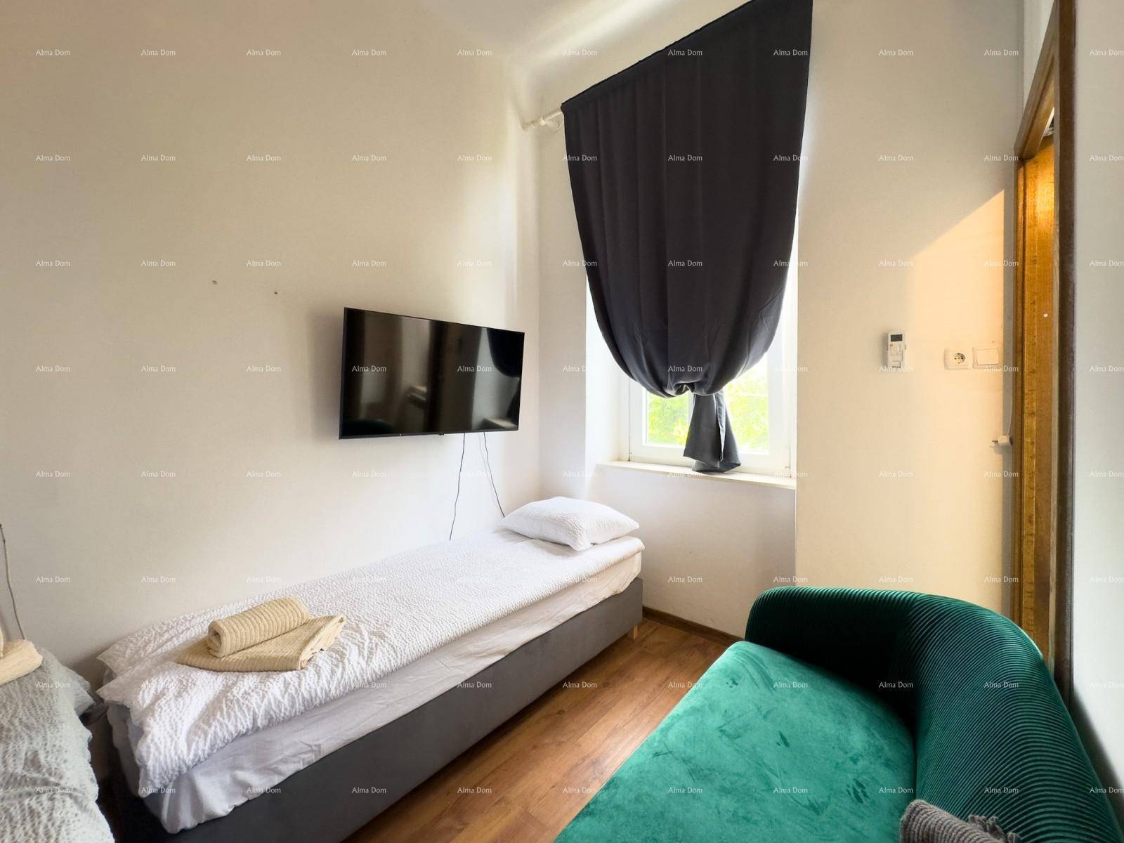 Schlafzimmer mit Einzelbett, einem bequemen grünen Sofa und einem an der Wand befestigten Fernseher.