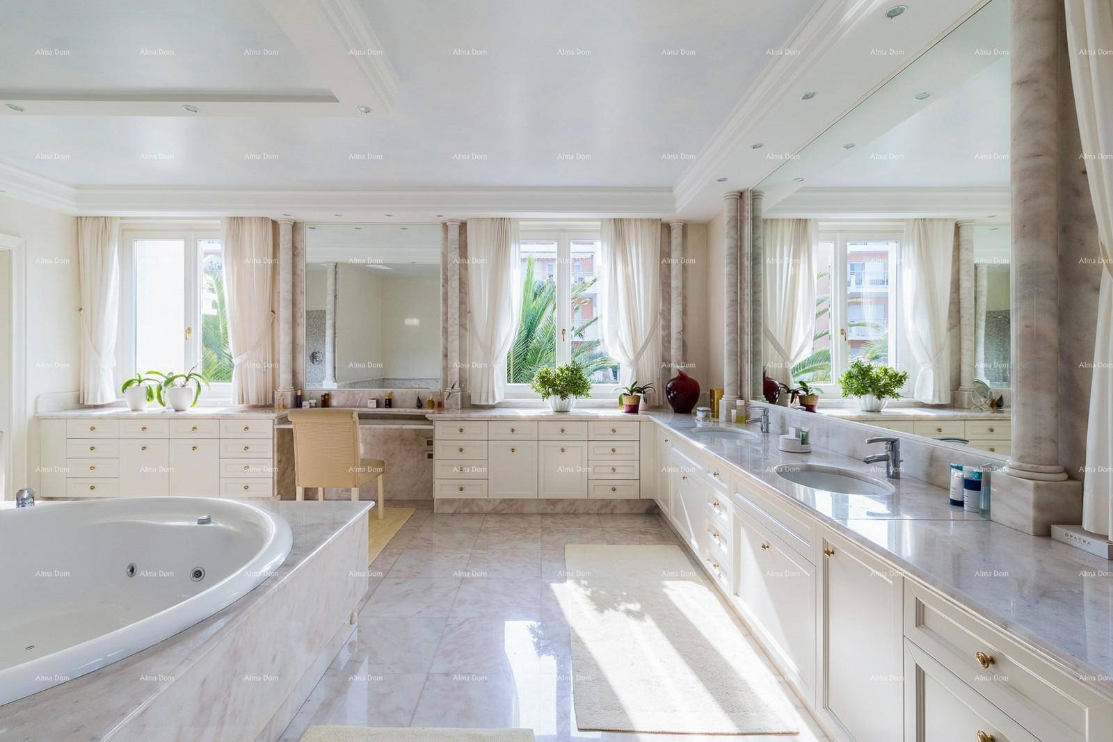 Luxuriöses Badezimmer mit Marmoroberflächen, Doppelwaschbecken, Badewanne und viel Tageslicht.