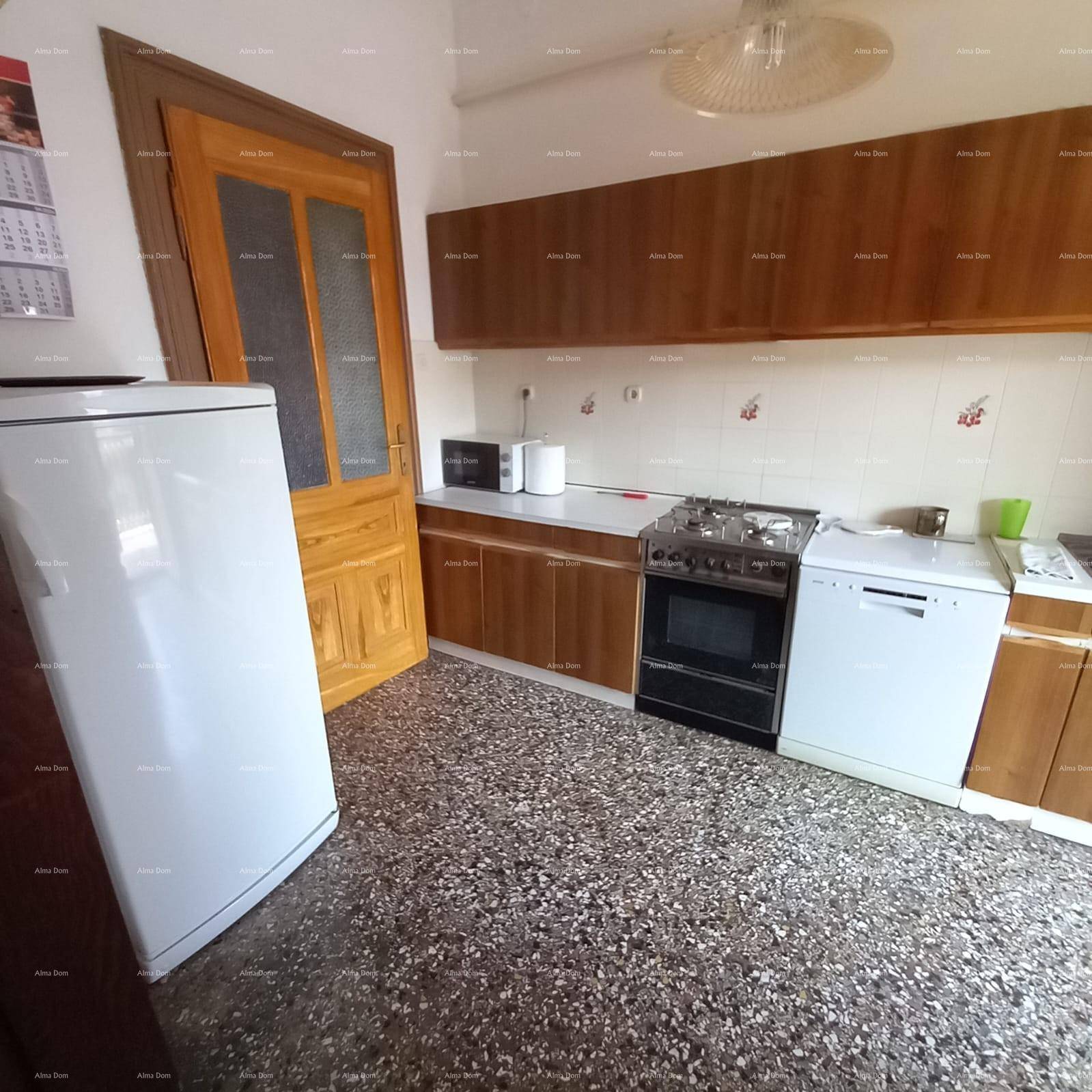 Einfache Küche mit Holzschränken, Gasherd und Terrazzoboden.